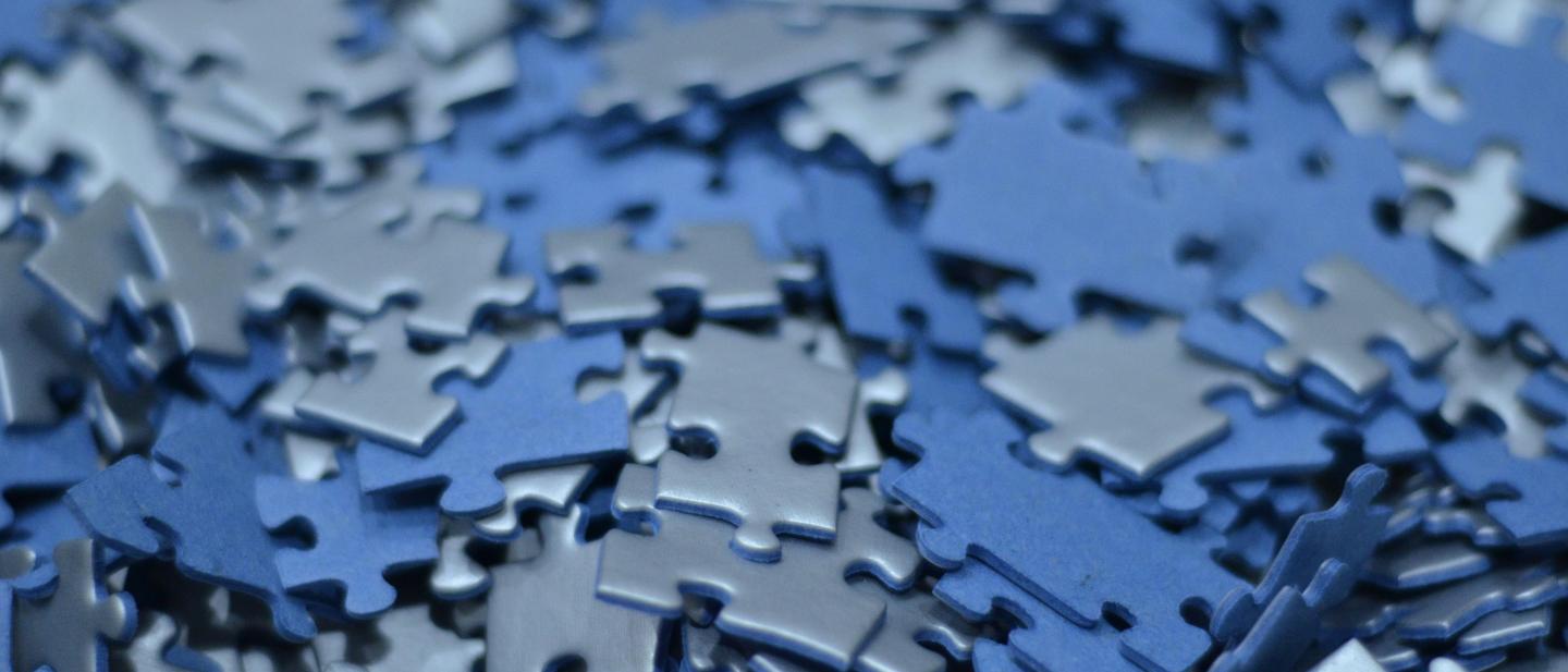 A close up of a pile of blue plastic pieces of a puzzle
