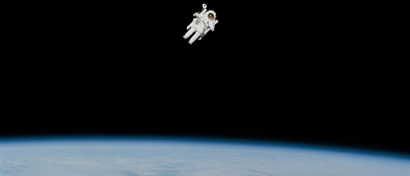 Astronaut in spacesuit floating in the space with Earth below them